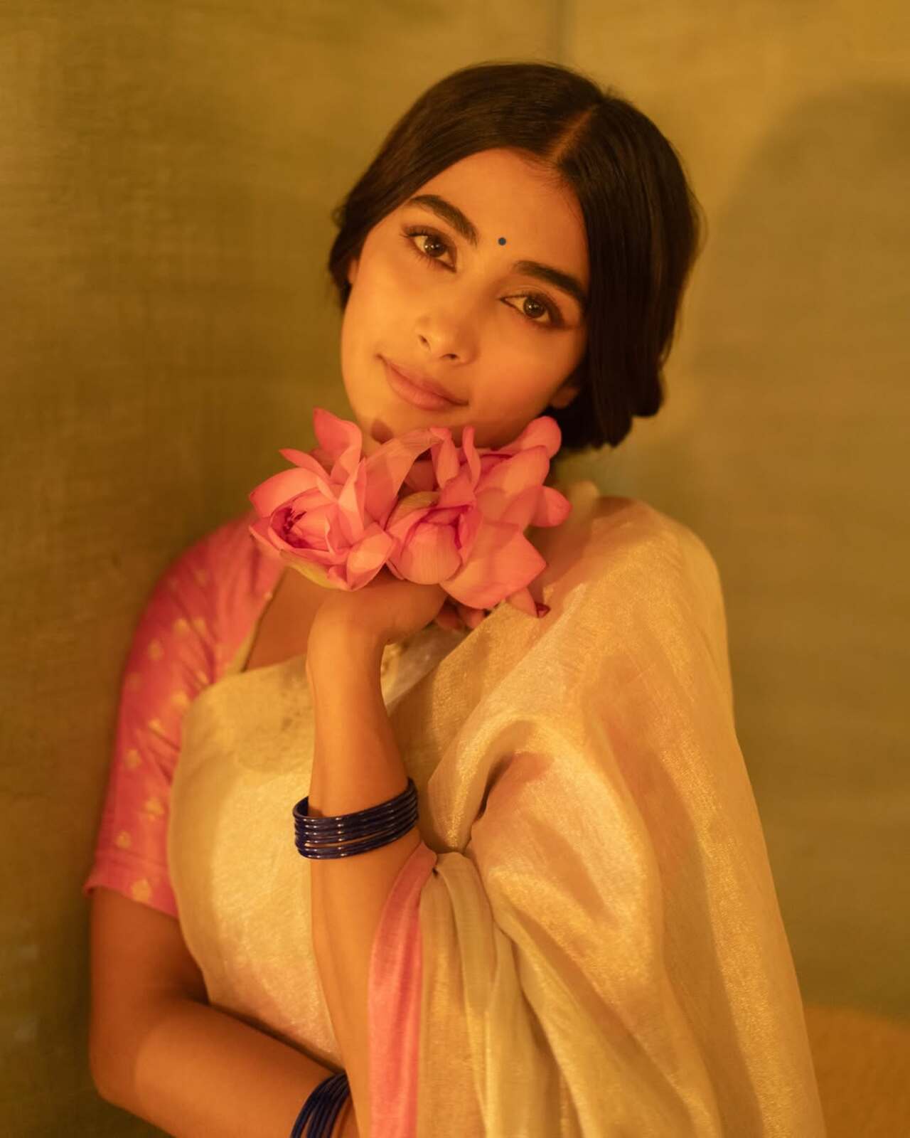 For the promotions of Retro, Pooja Hegde channelled soft retro energy in a pink and ivory silk saree with golden accents. She styled her hair in a loose braid, accessorised her look with a pearl choker, a pendant neckpiece and glass bangles